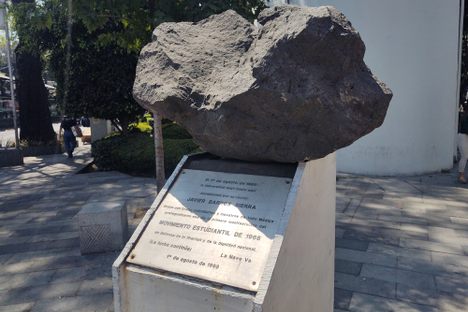 A volcanic rock sits on a pedestal in a park