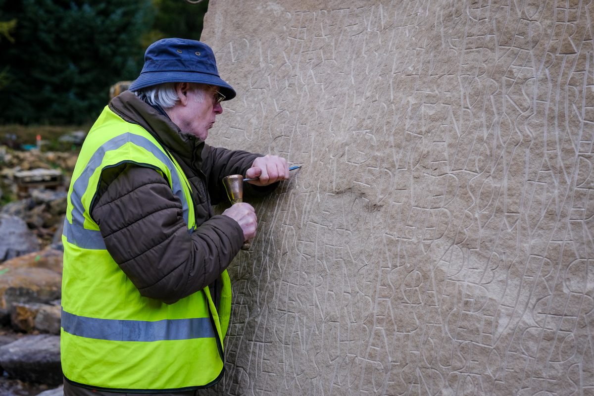 Artisan Charles Smith carves a poem into a large boulder. Works by regional artists will be incorporated throughout the maze.
