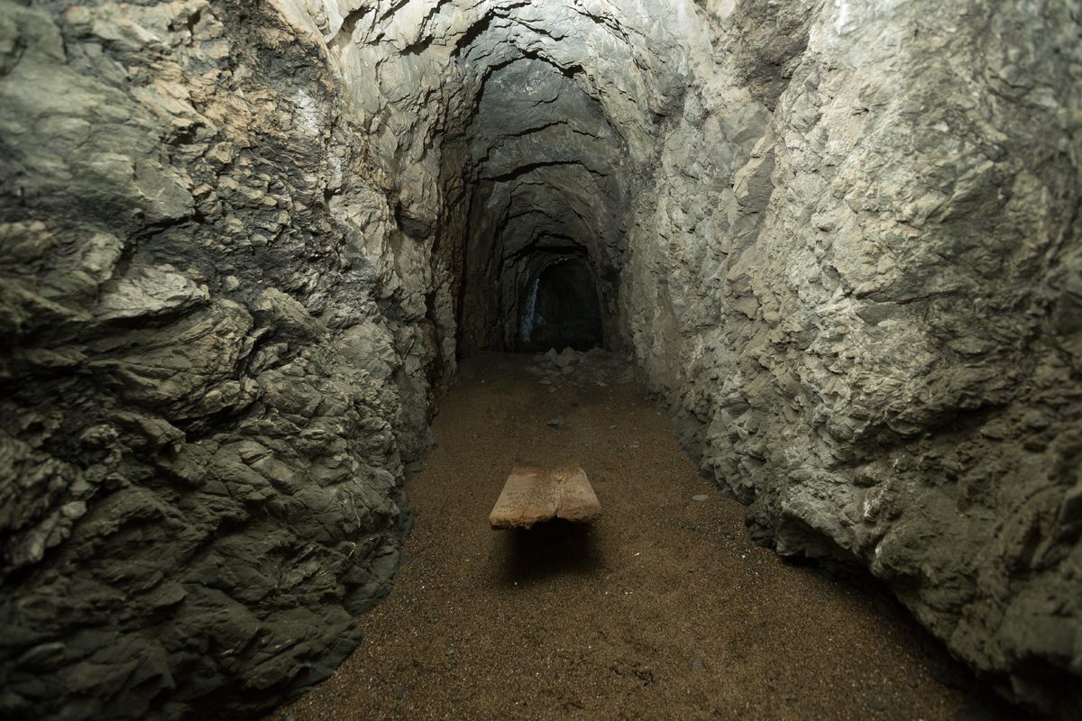 A wooden plank is buried under sand, deposited over decades of high tides washing into the cave.