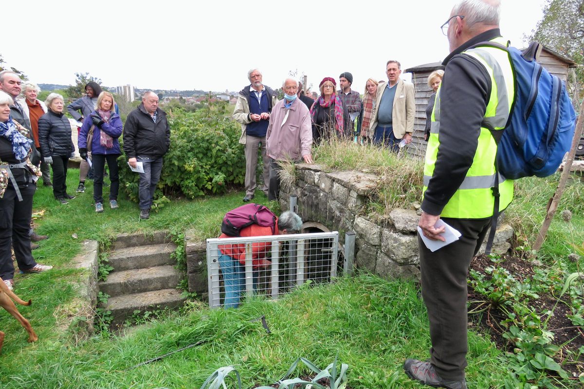 Pipe walk participants begin the annual inspection at an ancient well now surrounded by community garden allotments.