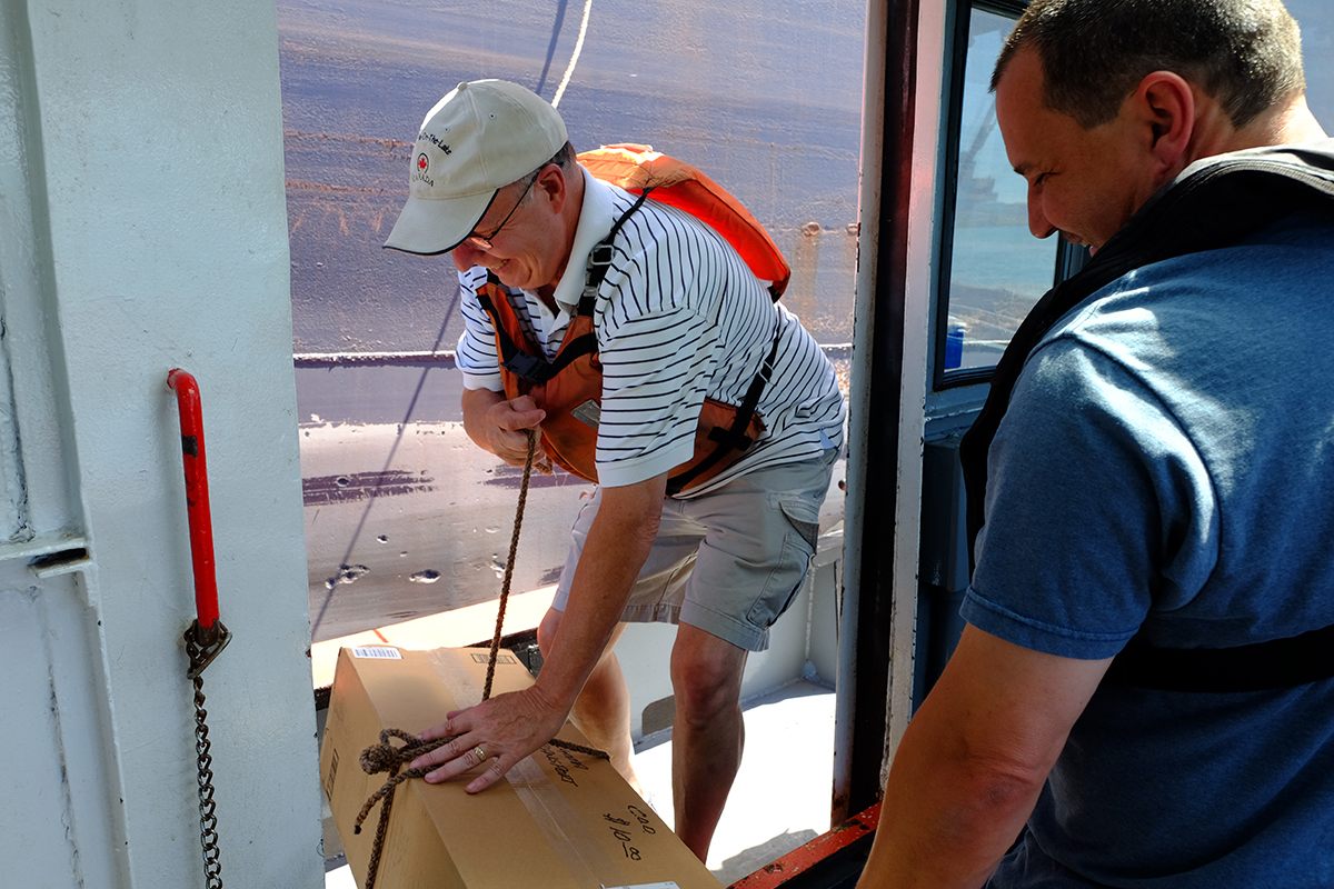 Bill Redding secures a package on board the <em>J.W. Westcott II</em> just before it is pulled up by a freighter. Delivering mail 24 hours a day, seven days a week, the boat pulls up next to passing ships in the river several times a day to drop off parcels.