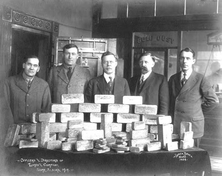 C.J. Lomen (center) and Carl Lomen (right) pose with Lomen & Company officers and a pile of gold bars.