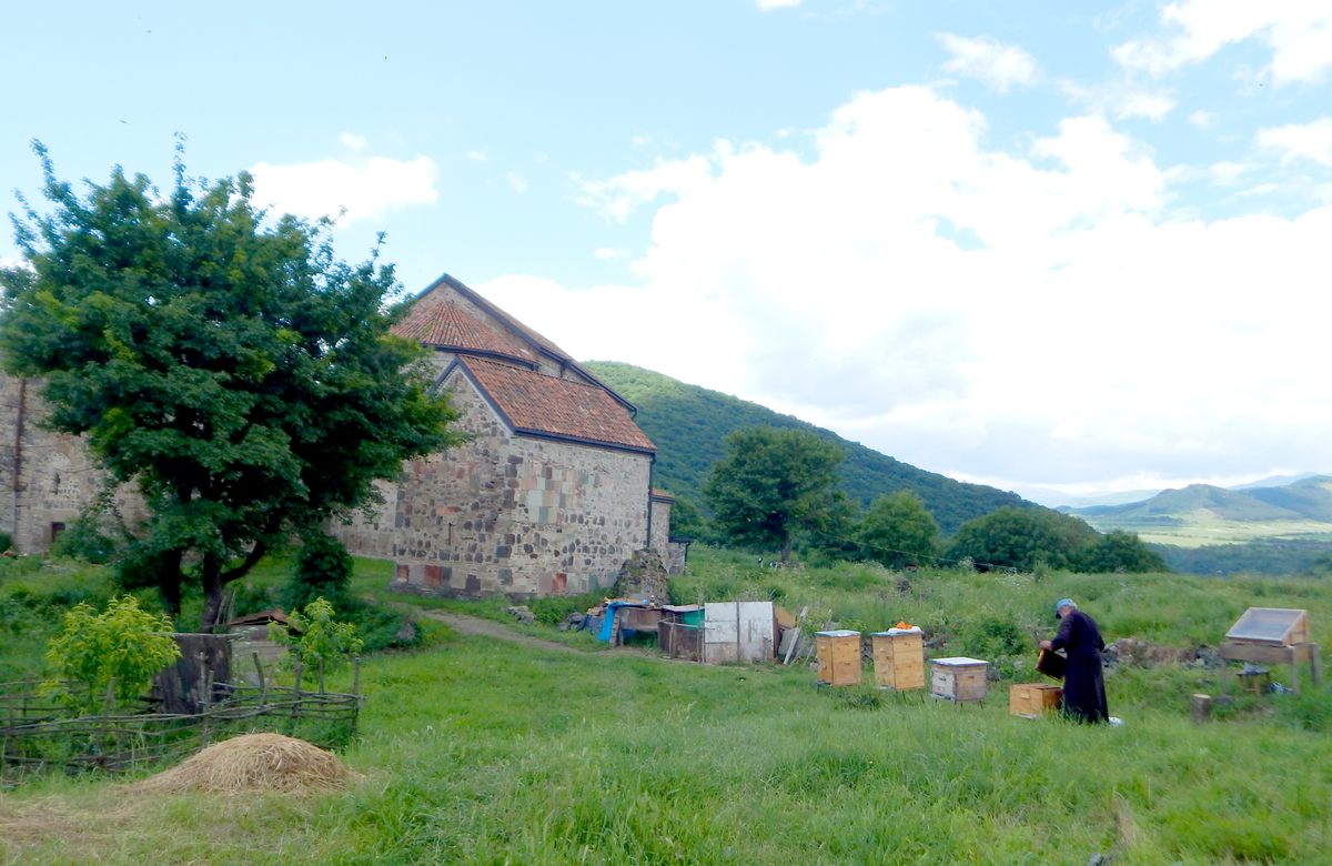 A monk tends honeybees beside Dmanisi's monastery, a short walk from one of the most important sites in paleoanthropology.
