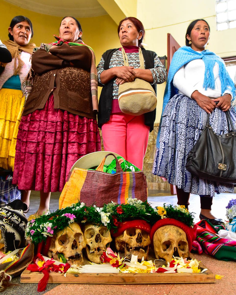 Several women stand behind their natitas while the chapel's priest reads an oration for the dead.