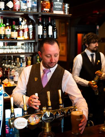 Bartenders pour up a particularly smooth pint of Guinness at The Guinea.