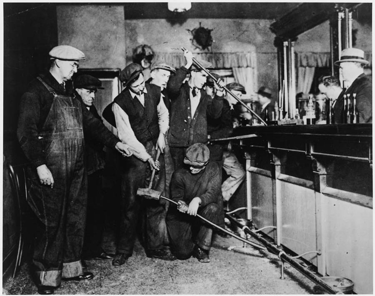 A group of Prohibition agents take crowbars to the bar.