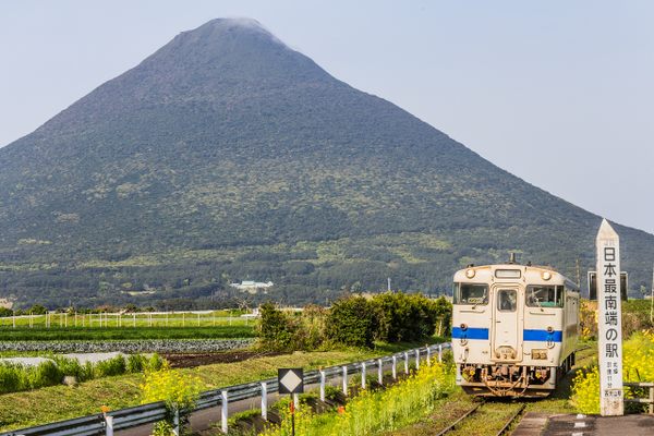 A train at Nishi-Ōyama Station, with Kaimondake in the background