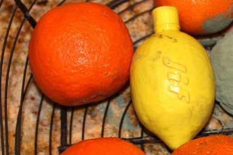 A jif lemon surrounded by oranges.