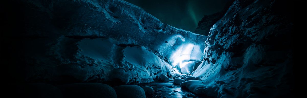 人闪亮的蓝色墙壁的冰川在冰岛晚上绿色条纹的北极光在天空。