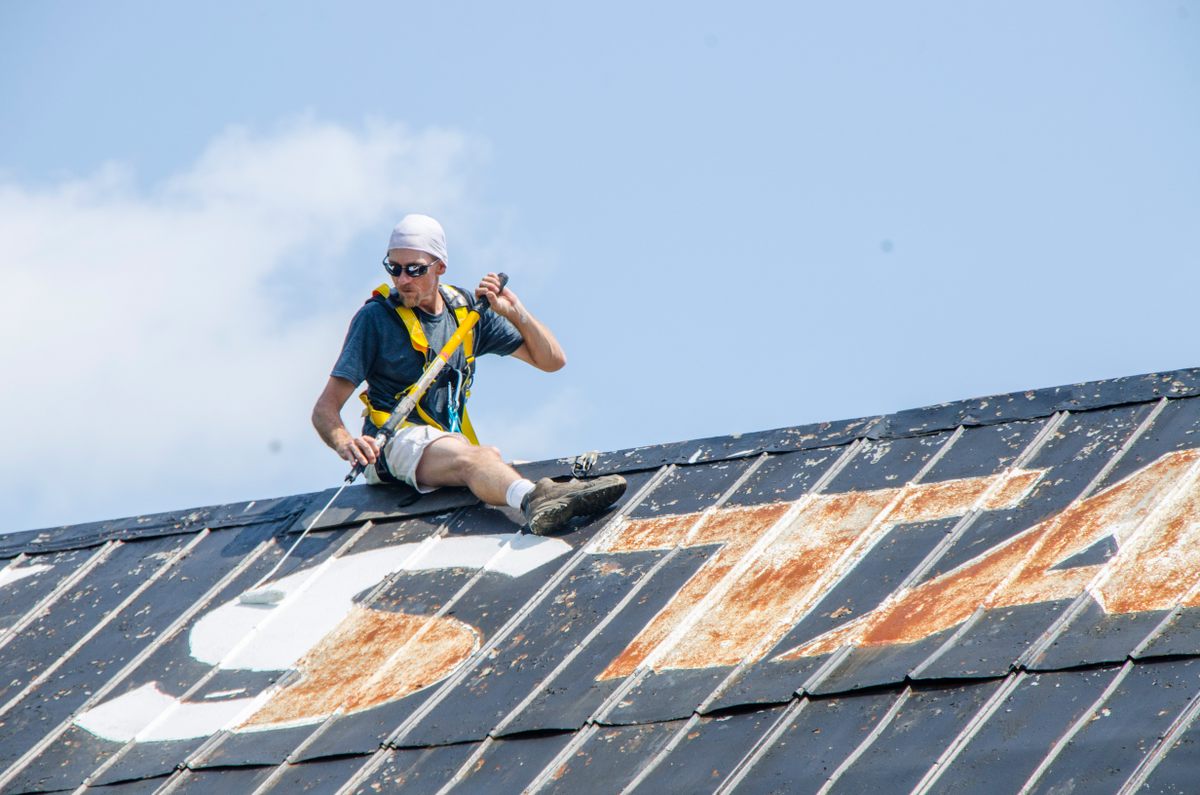 Brian Miller of H&M Painting repaints the roof of a barn in Crossville, Tennessee. The current owners purchased the property because of the mural.