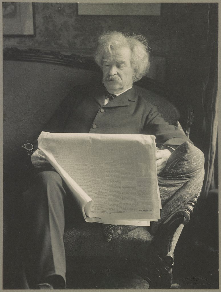 Mark Twain, reading a newspaper, 1902