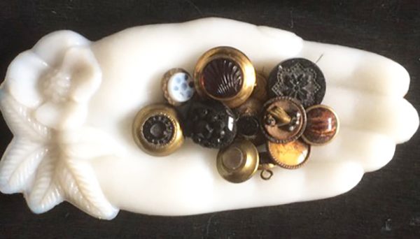 A hand-shaped tray holding buttons, one of which also features a bodiless hand.