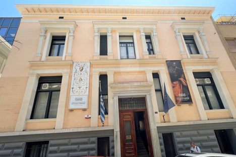 A neoclassical two-floor light pink mansion with five windows and a centered entranceway