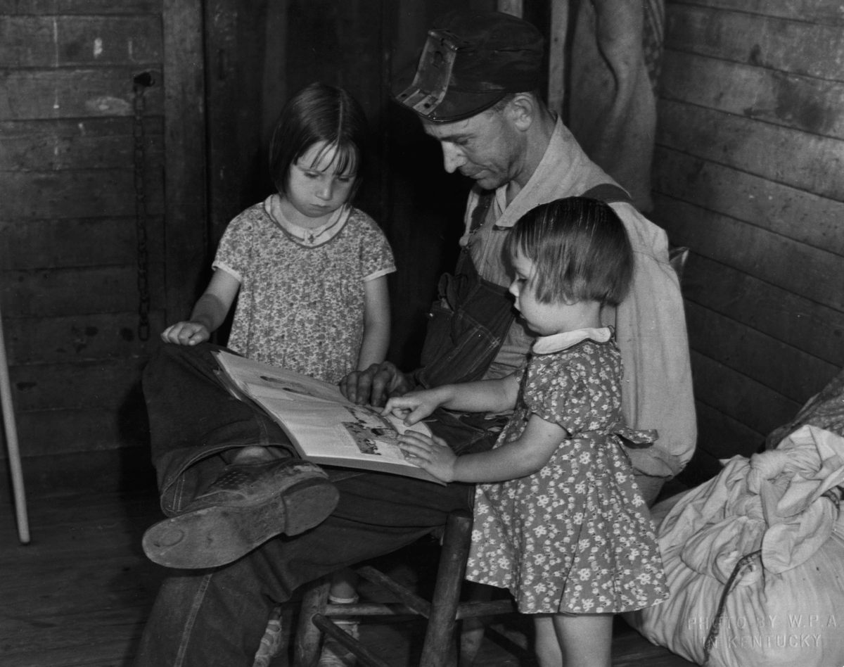 A man reading to two small children, c. 1940.