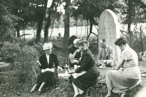 A small group picnics on ledger-style tombstones in Historic St. Luke's Ancient Cemetery. The photo is not dated but is believed to have been taken prior to St. Luke's 1957 Pilgrimage Service.
