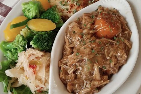 Schweinebraten, which consists of roasted pork in dark beer gravy, plus scalloped potatoes and mixed vegetables.