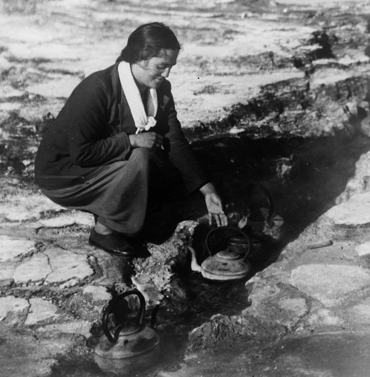 A Māori woman cooking in a hot spring in Rotorua, circa 1933. Before the availability of metal vessels, cooking in Aotearoa New Zealand typically involved placing heated stones in wooden containers.