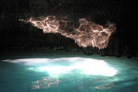 Sunlight from the dome’s opening plays on the surface of the spring water, reflecting on the rock face inside