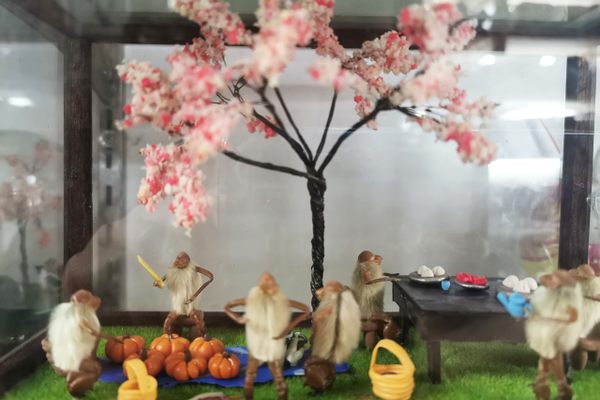 A hairy monkey diorama made by Ying Li, showing a picnic in the park and a vendor selling pumpkins.