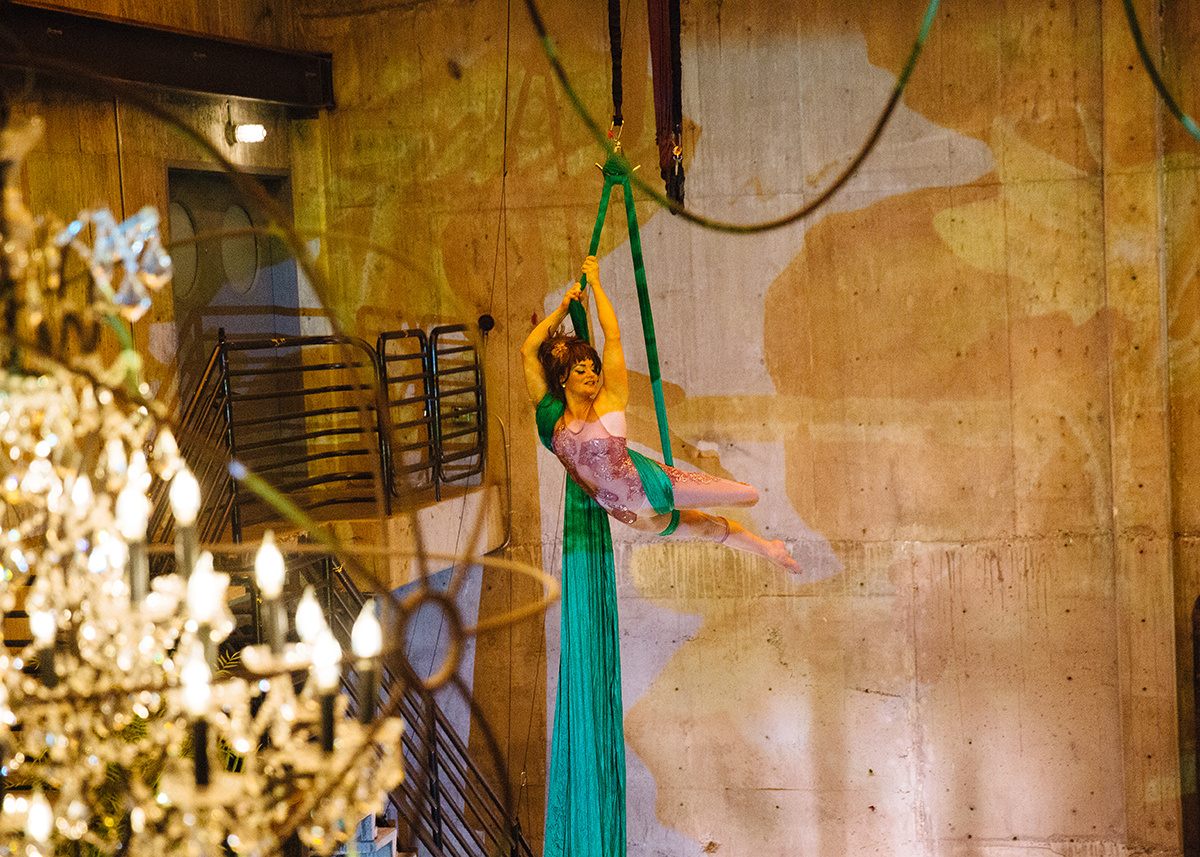 The aerialist Tanya Brno, suspended from silks that invoke the climbing vines of a creeping cucumber.