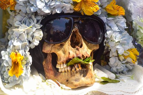 A natita sporting wide sunglasses and with a mouth full of coca leaves.