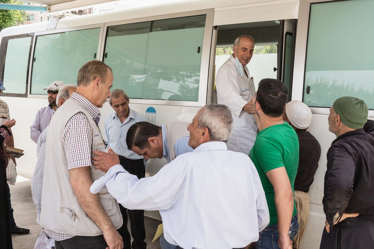Doctor Jamal Ismael (framed in doorway) talks to patients outside the Order of Malta Mobile Medical Unit in the village of Bakkifa, Lebanon.