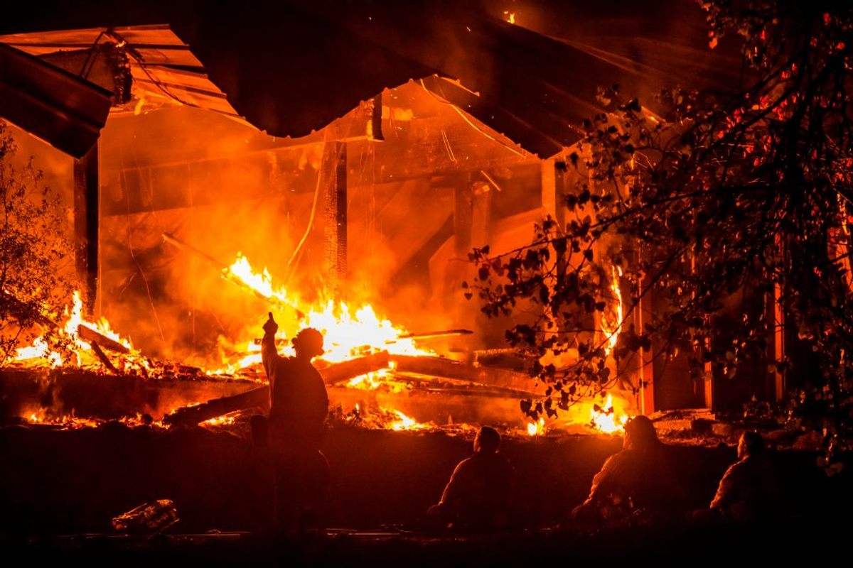 A firefighter gestures as a blaze consumes a building during the Kincade Fire of 2019.