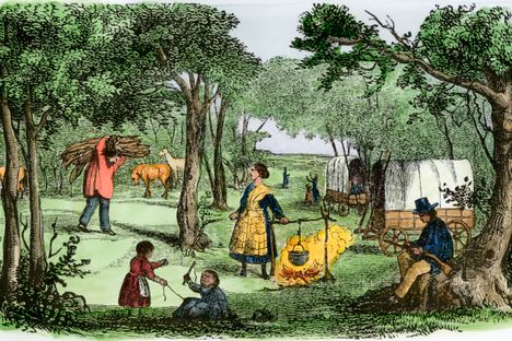 Pioneers camp at sunset along the Oregon Trail, 1850s.