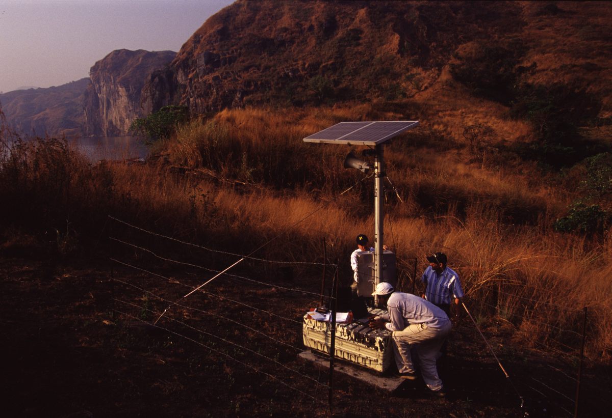 Cameroonian and American scientists perform maintainence on one of the carbon dioxide detectors deployed around the lake in the aftermath of the 1986 disaster. The detectors are part of an early warning system to alert area residents in the event of another toxic gas release.