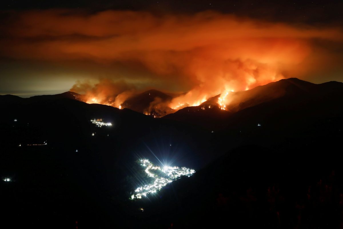 In September 2021, as a wildfire advanced, Genalguacil's lights can be seen at left in the background. The town of Benarrabá is in the foreground.