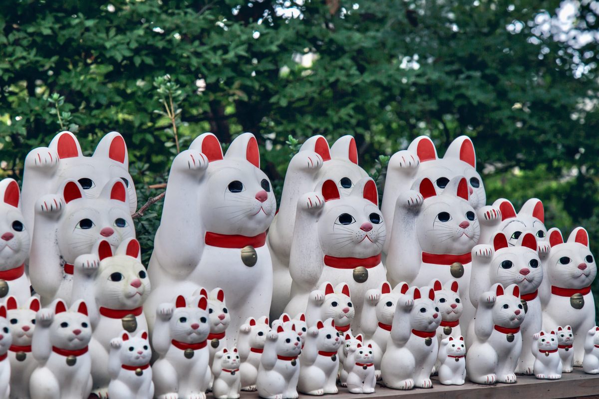 The Japanese <em>maneki-neko</em>—the beckoning cat, with one paw raised and “waving”—symbolizes luck.