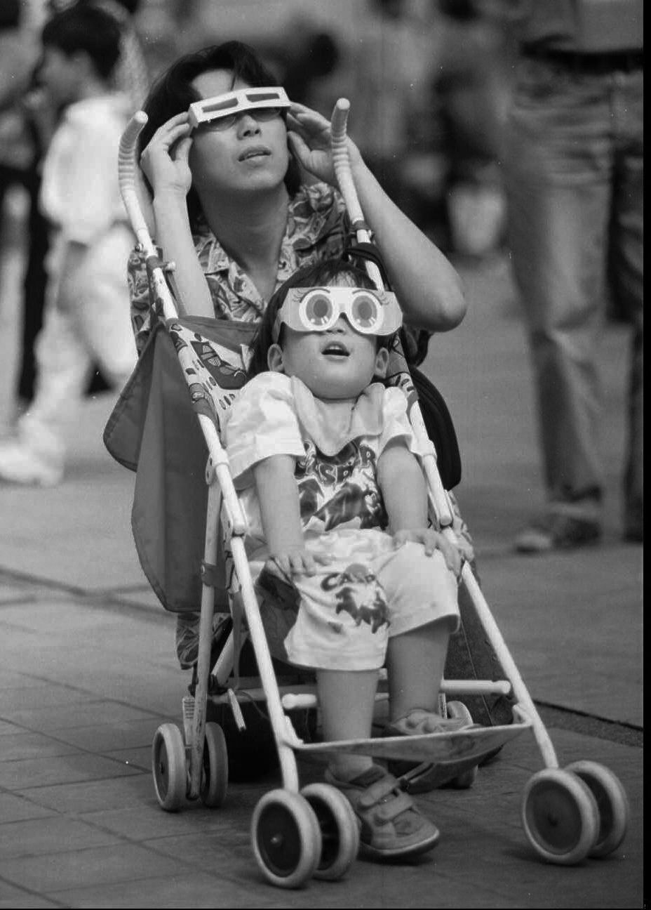 A mother and her son watch the solar eclipse in Bangkok, Thailand, 1995.