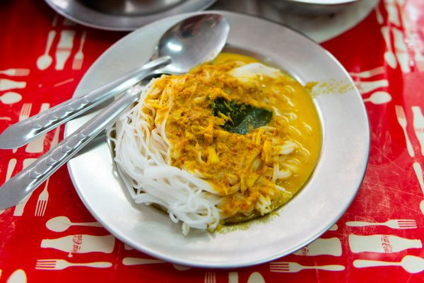 A plate of bouncy khanom jeen noodles gets topped with a fiery curry.