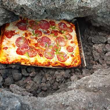 The heated lava rocks bake the pizza.