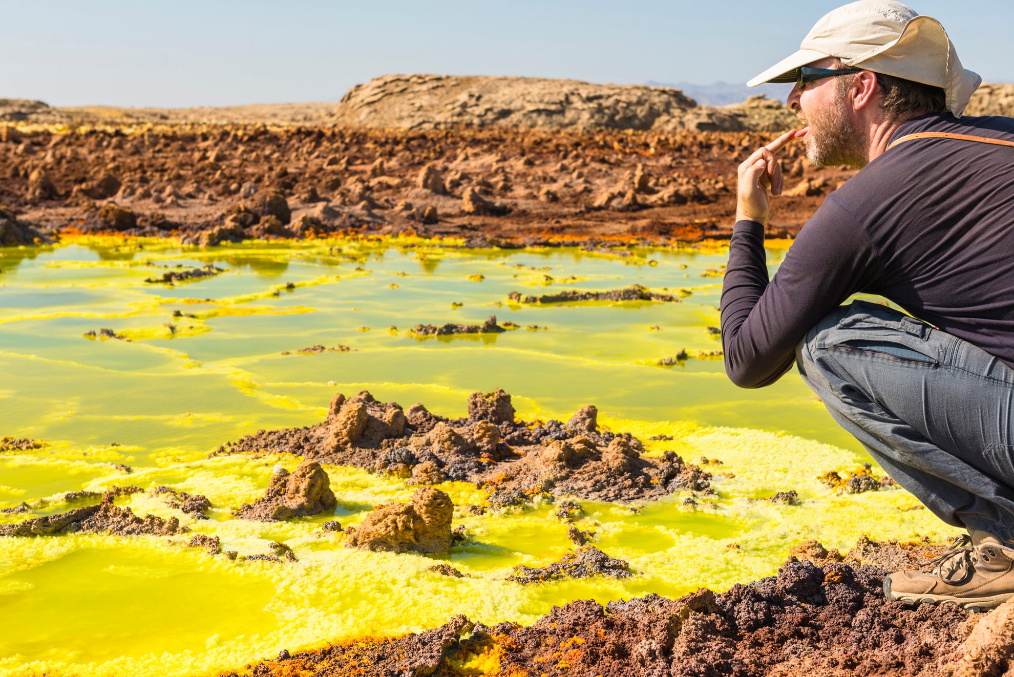 A tourist tastes salt water with his finger at Dallol's hot springs. 