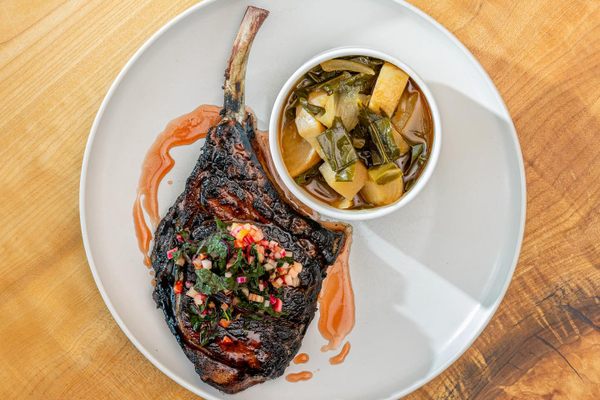 This ham-cured tomahawk pork chop is enlivened with a strawberry and hibiscus gastrique.