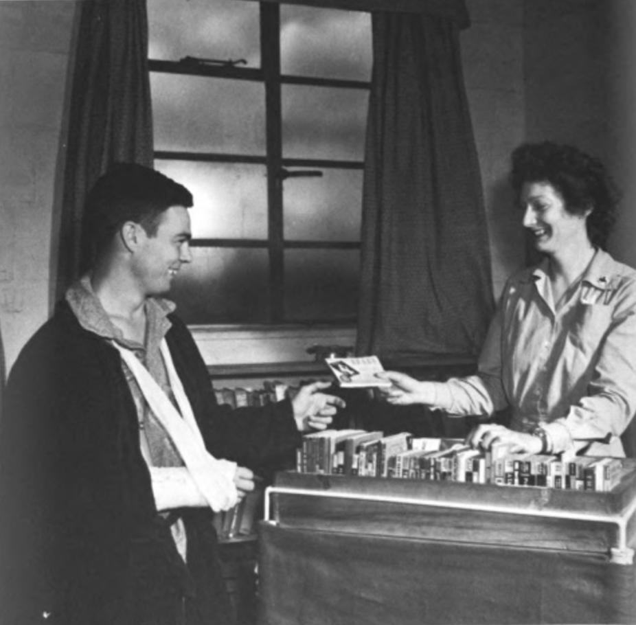 An soldier receives an Armed Services Edition from a librarian.