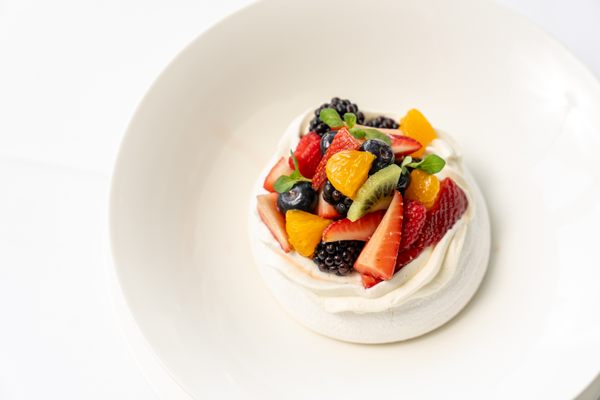 The pavlova comes crowned with jewel-like fruit.