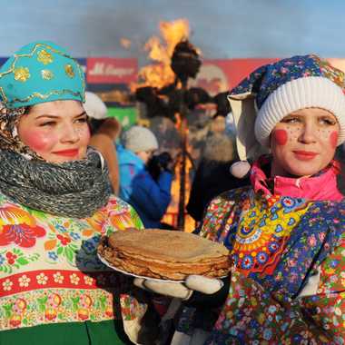 Young women, with blinis, and Lady Maslenitsa burning in the background.