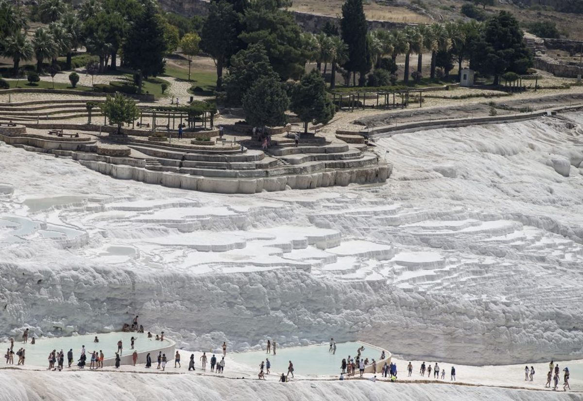 Tourists at the travertine pools at the Pamukkale of Turkey's Denizli Province, beneath the ruins off the ancient city of Hierapolis.