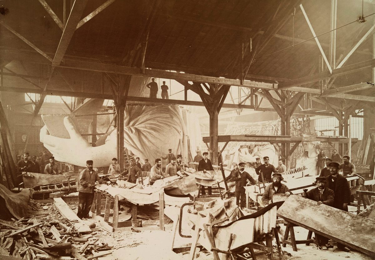 Men in a workshop hammering sheets of copper for the construction of the Statue of Liberty in 1883.