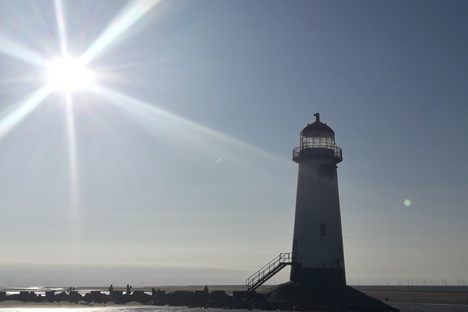 The lighthouse being seen farther by the beach.