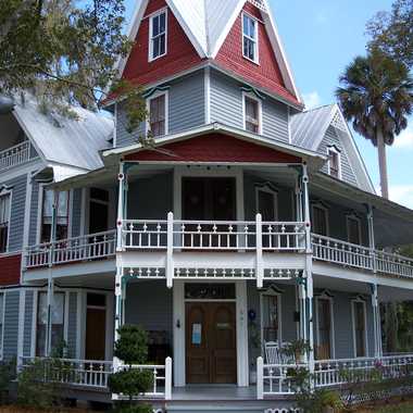 The imposing house is framed by tall palms and ancient, moss-covered oaks.