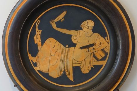 A plate depicting a woman ready to fire her shot with her kylix.