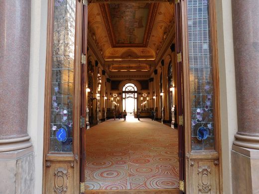 Two open doors look into an fancy, carpeted hallway
