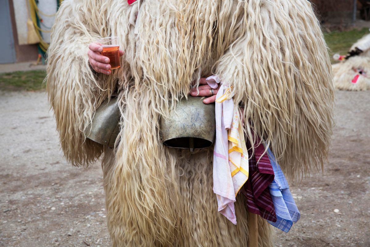 A Kurent holds a drink during his door-to-door rounds. Traditionally, only unmarried men were allowed to wear the Kurent costume, but not all residents can participate in festivities. 