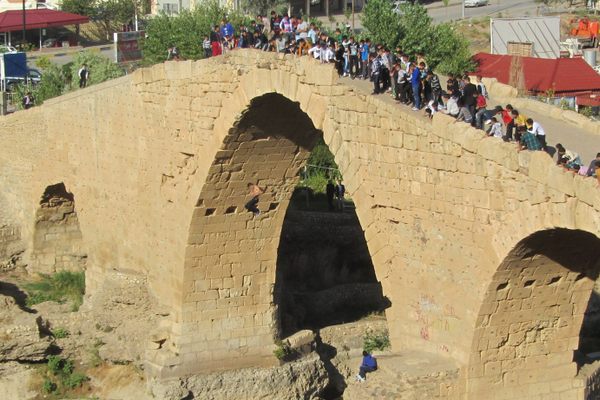 Zakho Bridge and people watching a young daredevil dive (barely visible against the inner vault of the arch). 