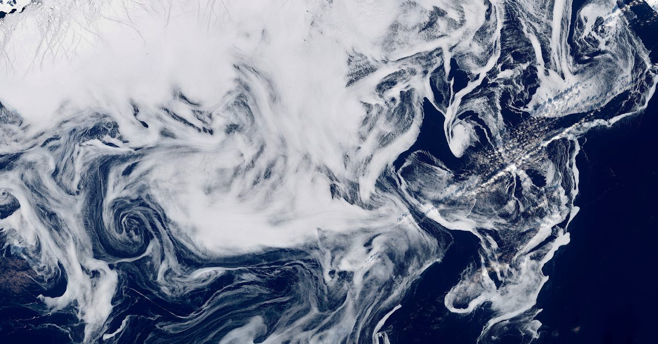 A satellite image from March 7, 2022, shows swirls of sea ice that resemble smoke—or a spectral apparition—against the deep blue North Atlantic. 