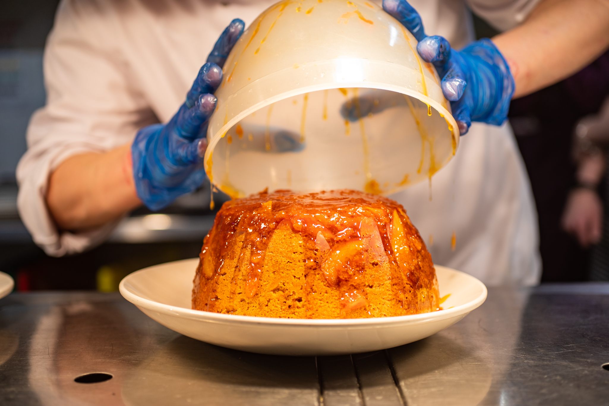 The process of unmolding an apple and syrup sponge pudding.