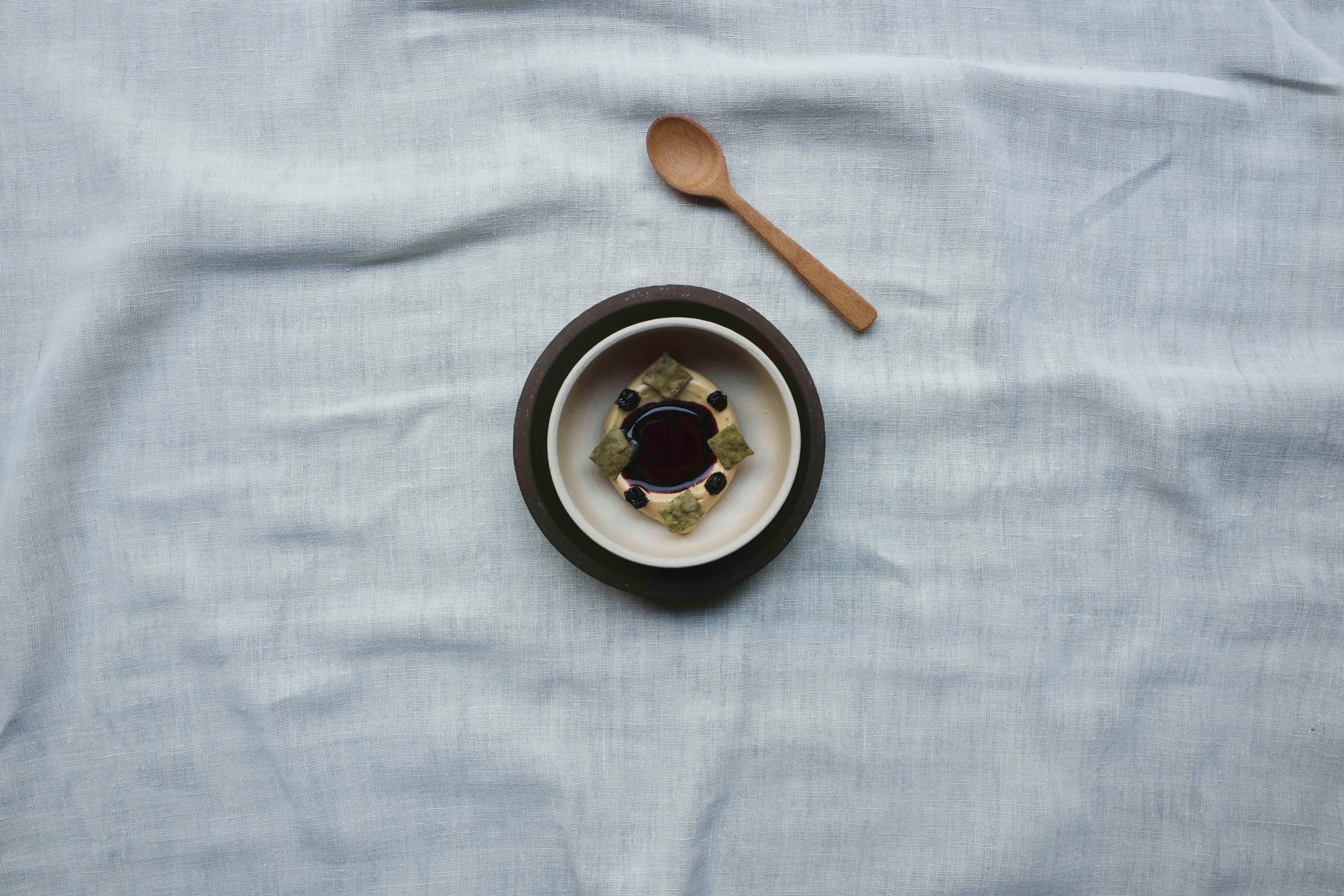 A dish of roasted pine bark and koji ice cream with pine-infused blueberry juice, crispy koji, and sweet cicely oil from Restaurant Grön in Copenhagen.